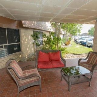 A cozy outdoor seating area with cushioned chairs and a glass-top table under a covered patio.