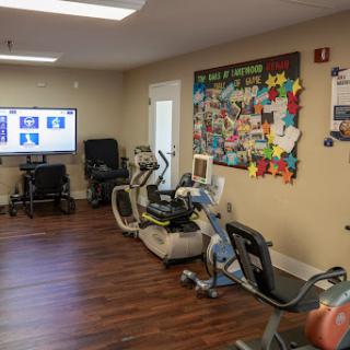 A well-equipped exercise room featuring various fitness machines and a colorful bulletin board.