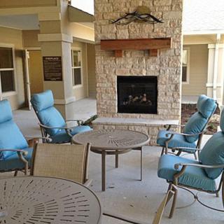 An inviting patio area with blue cushioned chairs and a stone fireplace.