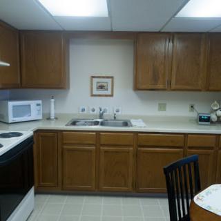 A well-organized kitchen featuring wooden cabinets, a microwave, and a dining area.