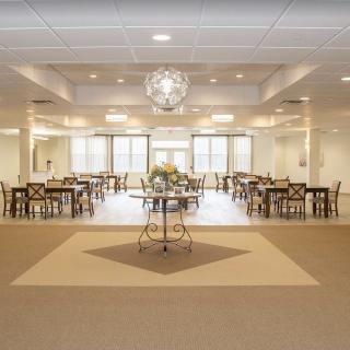 A spacious and elegant banquet hall with tables, chairs, and a central chandelier.