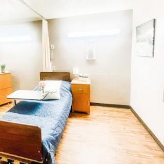 A well-lit hospital room featuring a bed and bedside furniture, designed for patient comfort.