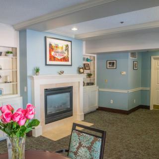 A cozy living room with a fireplace, artwork, and floral decor.