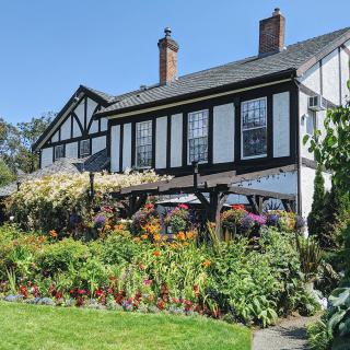 A charming Tudor-style house with a vibrant garden full of flowers.