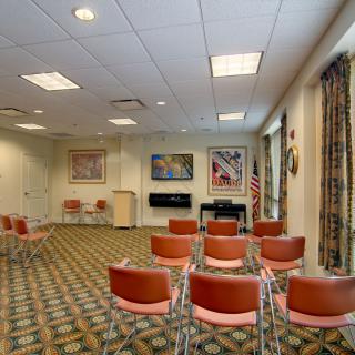 A conference room with rows of chairs facing a podium and artwork on the walls.