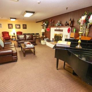 A cozy living room with a grand piano, comfortable seating, and a decorative fireplace.