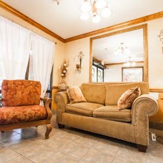 A cozy living room featuring a beige sofa and an elegant armchair, adorned with soft furnishings.