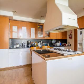 A modern kitchen with wooden cabinets and a central island featuring a stovetop.
