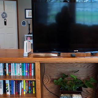 A cozy living room setup with a TV, bookshelf full of books, and a video game console.
