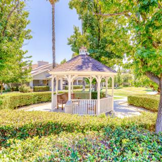 A picturesque gazebo in a beautifully landscaped garden on a sunny day.