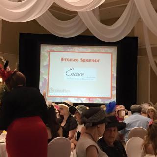 A formal event with a presentation screen displaying 'Present Sponsor' and people seated at banquet tables.
