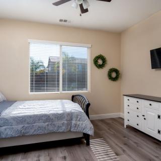 A modern bedroom with a bed, dresser, and wall-mounted TV.
