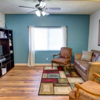 A cozy living room with a sofa, armchairs, and a colorful rug on hardwood flooring.