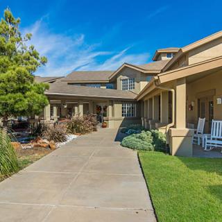 A spacious residential house with a large porch and landscaped front yard.