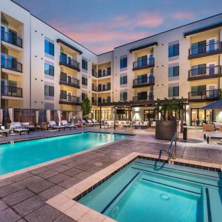 Modern apartment complex with a swimming pool and balconies at dusk.