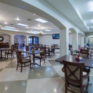 A modern dining area with neatly arranged tables and chairs, featuring elegant arches and soft lighting.