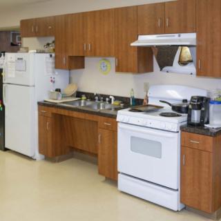 A kitchen with wooden cabinets, a refrigerator, stove, and sink.