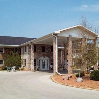 A two-story brick building with a covered entrance and surrounding landscaping.