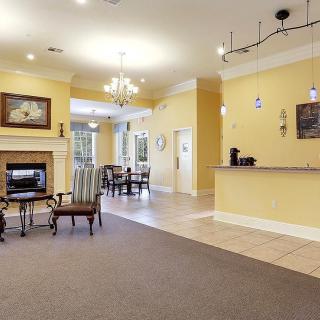 A spacious lobby area featuring a reception desk, chandelier, and a cozy fireplace.