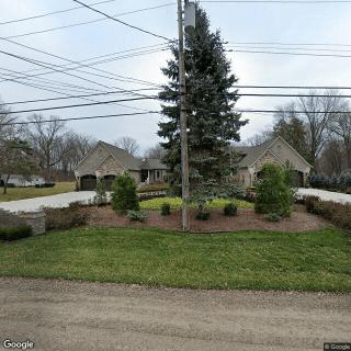 A suburban house with a landscaped garden, driveway, and power lines overhead.