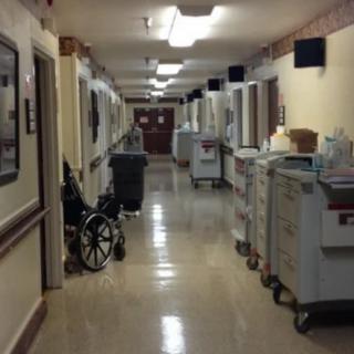 A hospital hallway lined with medical carts and a wheelchair.