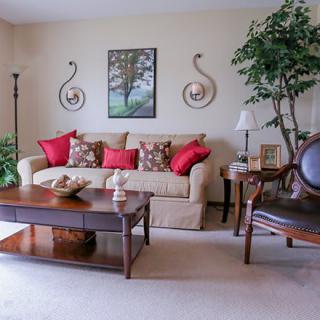 A cozy living room with a beige sofa, red pillows, and tasteful decor.