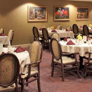 A dining room with elegantly set tables and upholstered chairs.