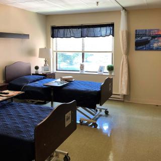 A clean, well-lit hospital room with two beds and a window.