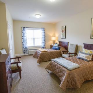 A cozy bedroom featuring two twin beds, a dresser, and comfortable seating.