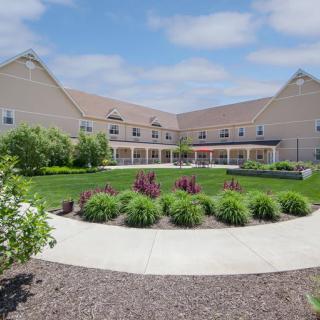 A residential building with a landscaped garden and pathway under a partly cloudy sky.
