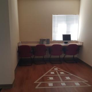 A minimalist workspace with computers and chairs in a well-lit room.