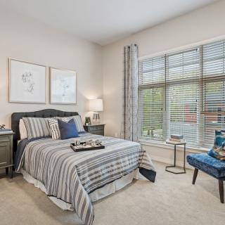A cozy bedroom with striped bedding and large window light.