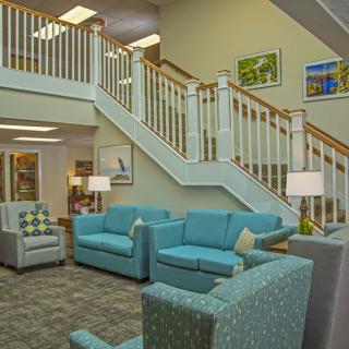 A cozy lobby area featuring teal sofas and a wooden staircase, adorned with modern lighting and artwork.