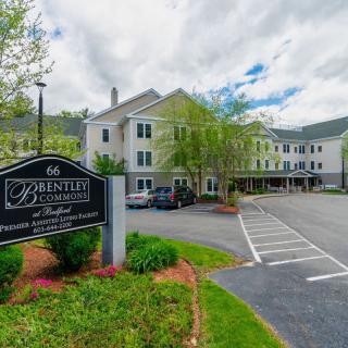 A hotel with a parking lot and surrounding greenery on a cloudy day.