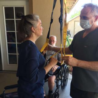 A caregiver assists a patient during a physical therapy session at home.