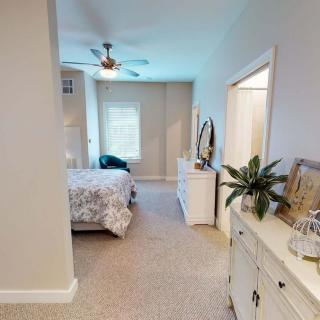 A cozy, well-lit bedroom featuring a bed, dresser, and ceiling fan.