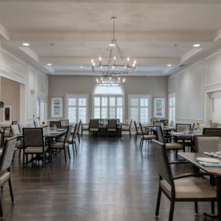 A spacious and elegantly designed dining room with chandeliers and arranged tables.