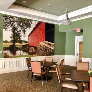 A cozy dining area with green walls and large wall art depicting a red barn.