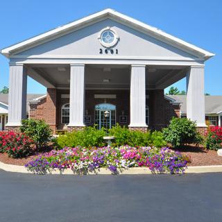An inviting building entrance with columns and a landscaped garden.