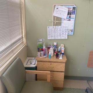 A small room corner featuring a wooden desk with various personal care products, a calendar, and wall decor.