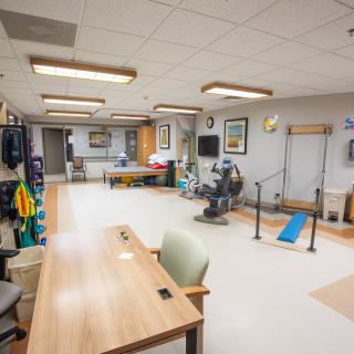 A well-equipped physical therapy room in a healthcare facility, featuring exercise equipment and therapy stations.