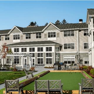 A modern residential building with a landscaped garden and seating area.