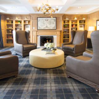 A cozy living room with armchairs, a fireplace, and bookshelves, creating a warm and inviting atmosphere.