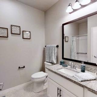 A modern bathroom featuring a large mirror, granite countertop with a sink, and wall decorations.