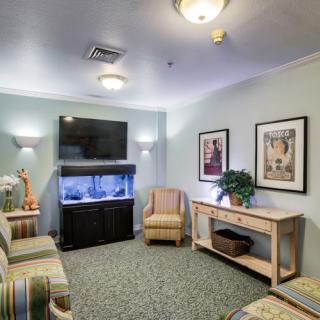 A cozy waiting room featuring an aquarium, comfortable seating, and a television.
