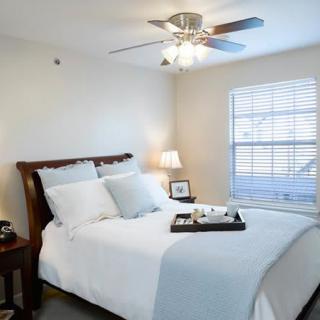 A cozy bedroom with a neatly made bed and a ceiling fan.