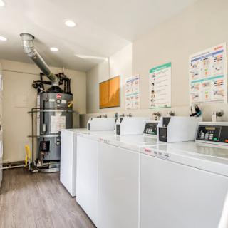 A modern laundry room featuring several washing machines and a dryer, designed for efficient use of space.