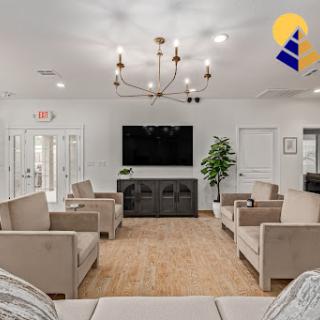 A modern living room featuring comfortable seating, a stylish chandelier, and a large television.