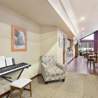 A cozy living space with a keyboard, patterned chair, and dining area.