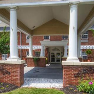 The image shows the entrance of a brick building with white columns.